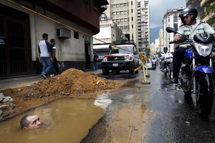 Một công nhân dầm mình trong nước để sửa chữa đường ống bị vỡ ở Caracas, Venezuela ngày 26/9